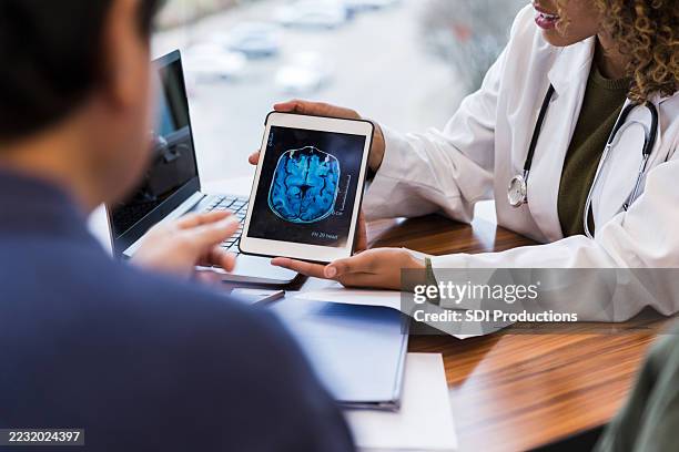 arzt zeigt dem patienten den mrt-scan auf dem tablet - hirntumor stock-fotos und bilder