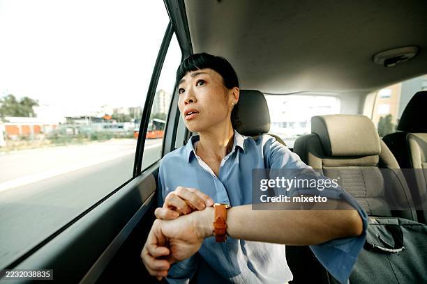 geschäftsfrau, die während der fahrt im auto auf die uhr schaut - auf die uhr sehen stock-fotos und bilder