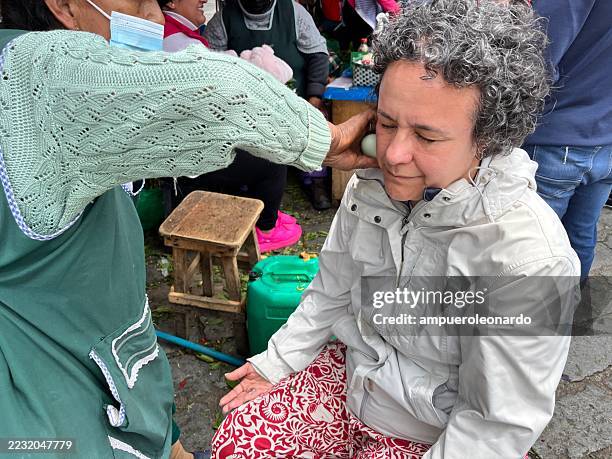vendor using egg for cleansing ritual on tourist in cuenca, ecuador - traditional native american medicine stock pictures, royalty-free photos & images