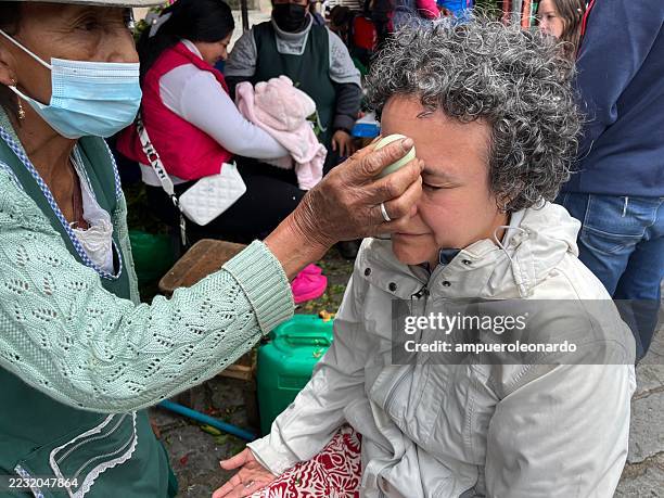 indigenous woman performing a cleansing ritual with an egg in cuenca - traditional native american medicine stock pictures, royalty-free photos & images