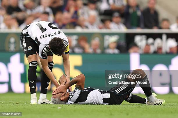 Joelinton of Newcastle United goes down with an injury as he is consoled by teammate Tino Livramento during the Premier League match between...