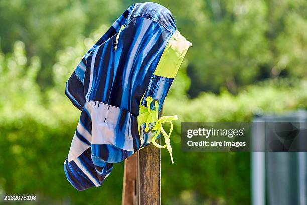 blue and yellow swim shorts hanging on wooden pool ladder to dry - zwembroek stockfoto's en -beelden