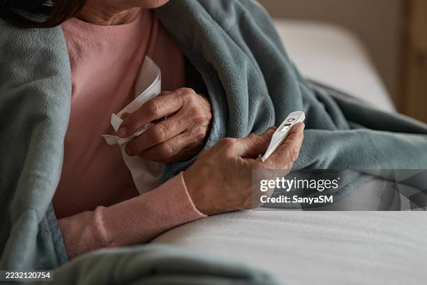 senior woman having cold and flu - wrapped in a blanket stock pictures, royalty-free photos & images