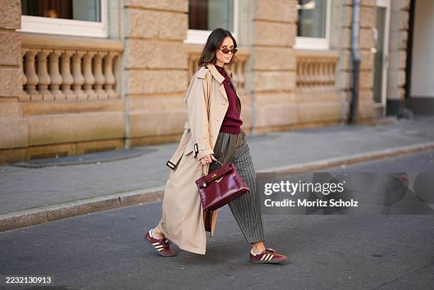Patricia Wirschke is seen wearing a Anna V Berg burgundy knit polo sweater with three buttons, collar and ribbed hem; a classic beige long Herno...