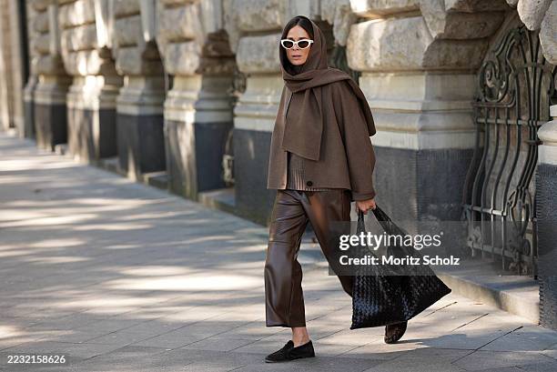 Patricia Wirschke is seen wearing a Max Mara wool blend buttoned cape in brown hue with a sewn on scarf; a warm grey Max Mara sweater with ribbed...