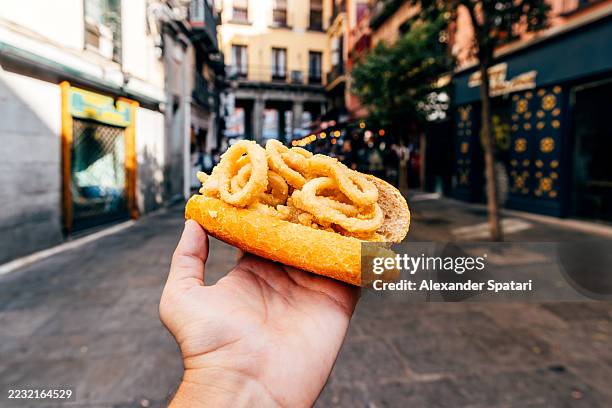 person holding bocadillo de calamares (calamari sandwich)on the street in madrid, personal perspective view, spain - appetizer stock pictures, royalty-free photos & images