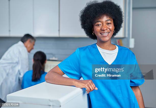 friendly medical staff member smiling in clinical reception area - nursing assistant stock pictures, royalty-free photos & images