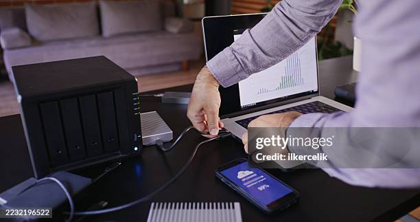 man backing up his data using cloud, solid state drives (ssd), and network attached storage (nas) in the office - computer loading stock pictures, royalty-free photos & images