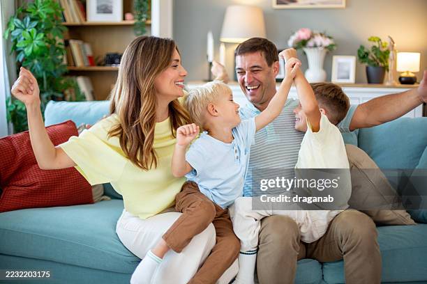 happy family having fun and playing together on sofa at home - family excitement stock pictures, royalty-free photos & images