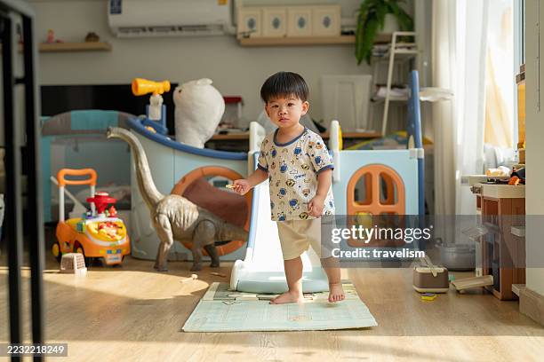 niño pequeño asiático feliz se ríe alegremente mientras juega en un juguete deslizante de plástico, demostrando el desarrollo motor grueso y la regulación emocional a través de la exploración activa del juego y las experiencias de aprendizaje senso - mentalidad fotografías e imágenes de stock