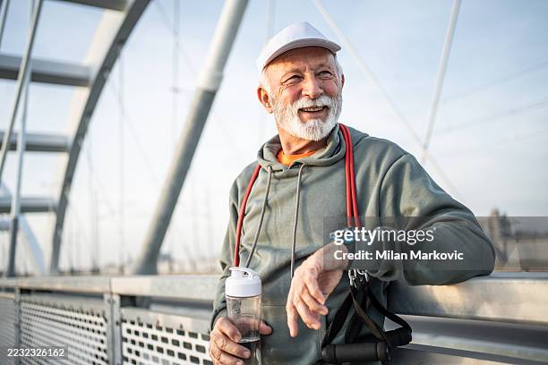 senior man resting after exercising on bridge - actieve ouderen stockfoto's en -beelden