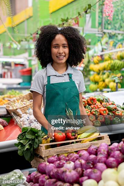 retail clerk filling a basket with fruits and vegetables while preparing a delivery order - groente en fruitkraam stockfoto's en -beelden