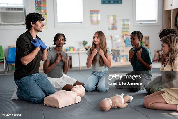 diverse group of students learning cpr from an instructor in a classroom setting - cpr training stock pictures, royalty-free photos & images