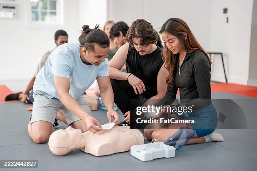 Diverse Group Practicing CPR Training Using AED Equipment in Classroom Setting Diverse Group Practicing CPR Training Using AED Equipment in Classroom Setting