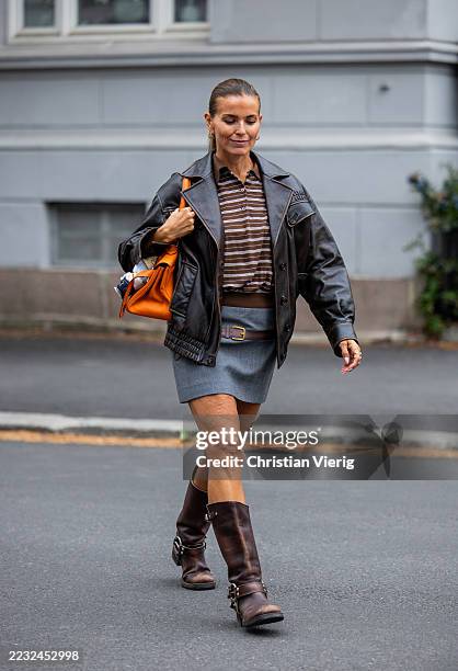 Janka Polliani wears leather jacket, grey skirt, orange Hermes bag with Labubu puppet during Oslo Fashion Week on August 27, 2025 in Oslo, Norway.