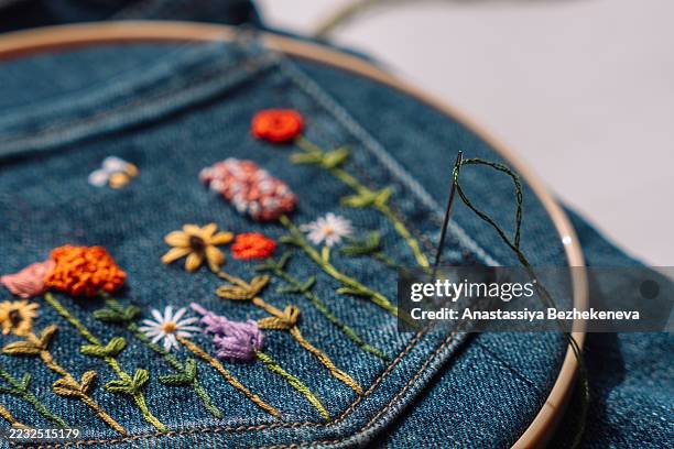 needle and green thread stitching floral embroidery on denim pocket - embroidery stock pictures, royalty-free photos & images