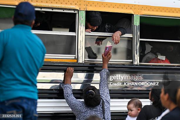 Woman shows a cellphone to a Guatemalan migrant deported from the United States inside a bus after his arrival at the Guatemalan Air Force Base in...
