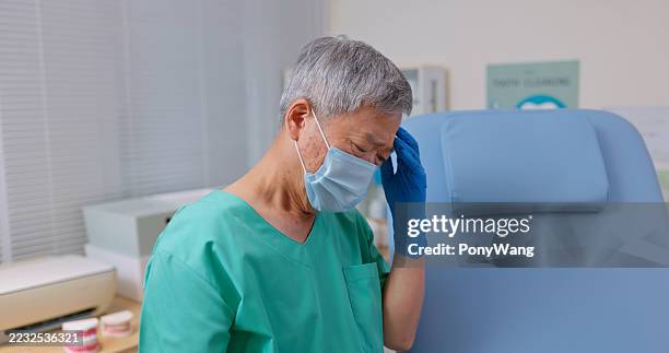 asian elderly male dentist felt depressed - wearing mask side view stock pictures, royalty-free photos & images