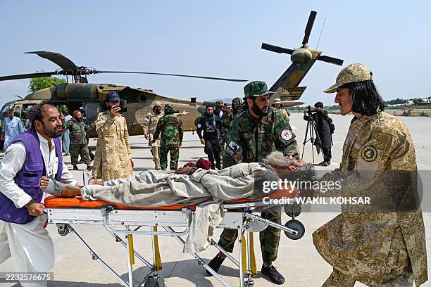 Afghan volunteers and Taliban security personnel carry an earthquake victim evacuated by a military helicopter from the Nurgal district of Kunar...