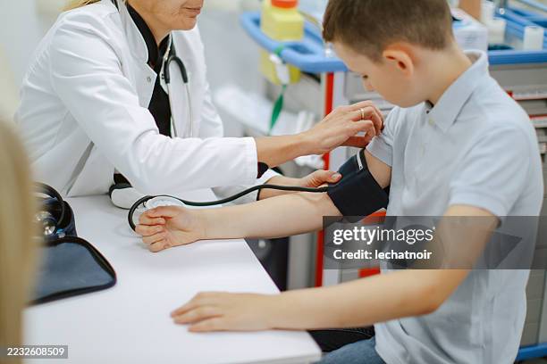 arzt misst den blutdruck eines kleinen jungen im krankenhaus - bluthochdruck stock-fotos und bilder