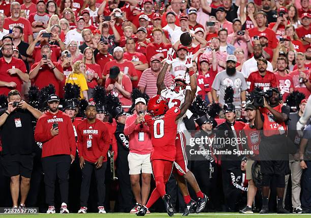 Wide receiver Nyziah Hunter of the Nebraska Cornhuskers catches a pass in the end zone for a touchdown as cornerback Matthew McDoom of the Cincinnati...