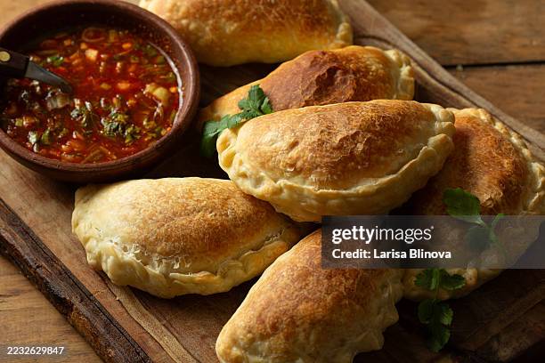 latin american empanadas with chili sauce on wooden board - cultura sudamericana fotografías e imágenes de stock