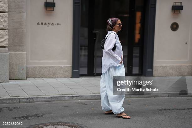 Anna Winter is seen wearing light blue oversized balloon pants with elasticated cuffs from The Frankie Shop; a white relaxed fit button-down cotton...