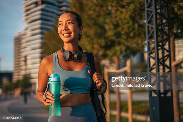 young sportswoman walking in the city after training - golden hour stock pictures, royalty-free photos & images