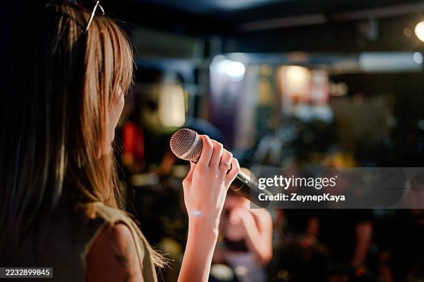 performer hält mikrofon auf der bühne mit blick auf das publikum - stand up comedy stock-fotos und bilder