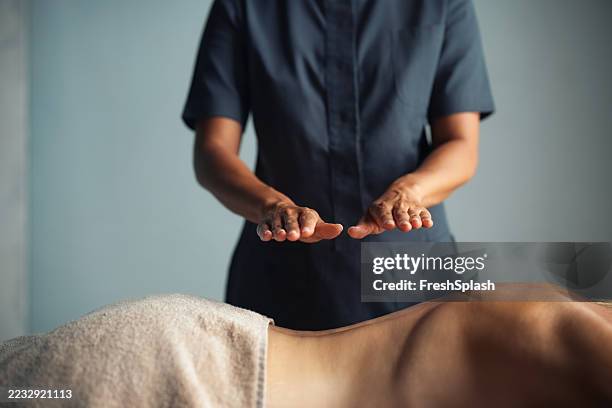 terapeuta profesional que realiza curación de reiki en un ambiente tranquilo de spa - reiki fotografías e imágenes de stock