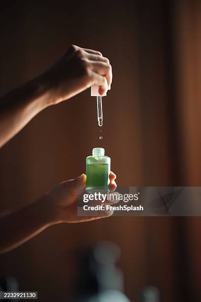 contagocce a mano con liquido verde in bottiglia di vetro su sfondo marrone - aromaterapia foto e immagini stock