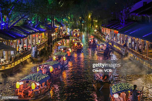 Tourists take a sightseeing boat on a river in the ancient town of Zhouzhuang at night on August 30, 2025 in Kunshan, Jiangsu Province of China.