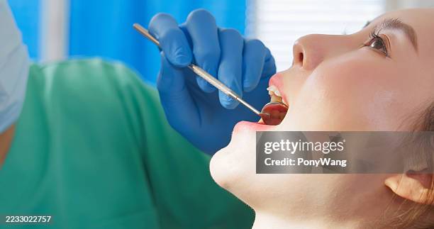 dentista masculino asiático examina los dientes femeninos del paciente - espejo dental fotografías e imágenes de stock