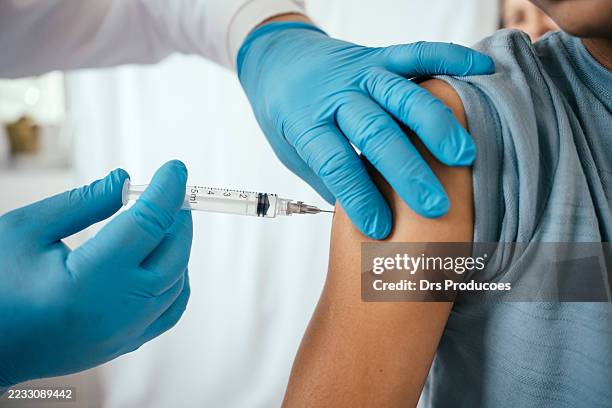 doctor administering vaccine to teenager in doctor's office - covid 19 vaccin stockfoto's en -beelden