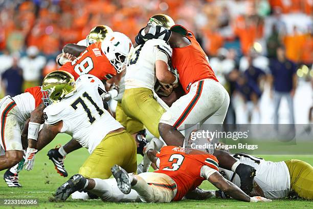 Akheem Mesidor and Rueben Bain Jr. #4 of the Miami Hurricanes sack CJ Carr of the Notre Dame Fighting Irish during the fourth quarter of the game at...