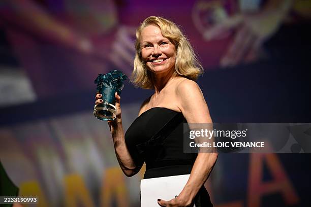 Actress Pamela Anderson poses holding her trophy after being awarded a Deauville Talent Award prize during the opening ceremony of the 51st edition...