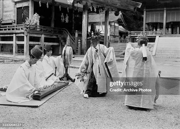 One person plays a koto as another sits behind a gong as dancers perform during a Shinto Festival in Japan, circa 1950.