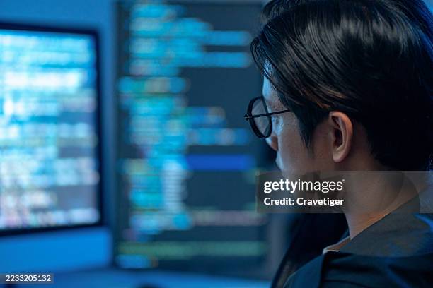 futuristic cybercrime scene: a hacker analyzes big data in a dimly lit office with multiple monitors. - developers coding stock pictures, royalty-free photos & images