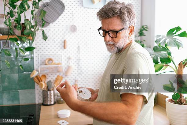 hombre revisando las baterías del detector de humo en casa - detector de humo fotografías e imágenes de stock