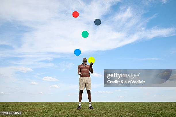 man juggling while colorful cut outs against sky - só um adulto de idade mediana - fotografias e filmes do acervo