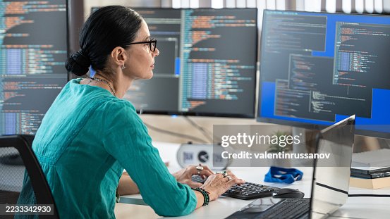 Female freelance developer coding and programming. Coding on two with screens with code language and application. Female freelance developer coding and programming. Coding on two with screens with code language and application.