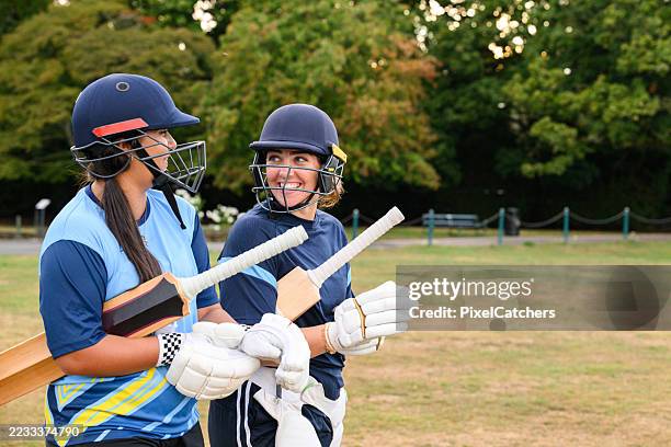female batsmen walking on to field with protective helmets, gloves and cricket bats - cricket team stock pictures, royalty-free photos & images