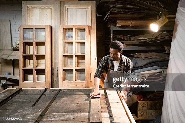 carpenter restoring and old door in workshop - houtwerkplaats stockfoto's en -beelden