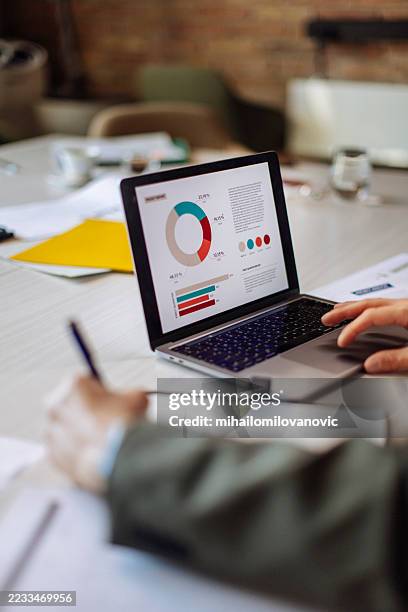 profesional de negocios que analiza datos en una computadora portátil en un entorno de oficina moderno - informe financiero fotografías e imágenes de stock