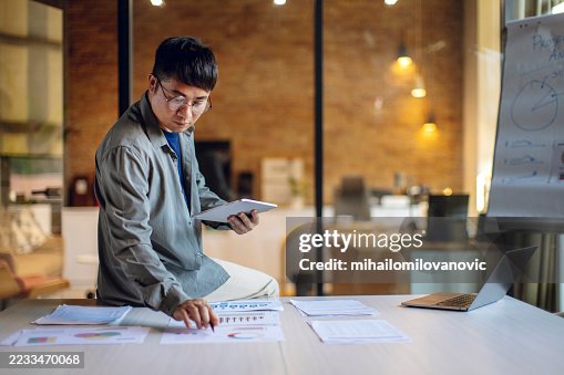 Focused Professional Analyzing Data Charts While Working in Creative Workspace Focused Professional Analyzing Data Charts While Working in Creative Workspace