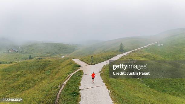 elevated/drone wide view of a runner on a trail in the mountains on a rainy summer's day - alternativ bildbanksfoton och bilder