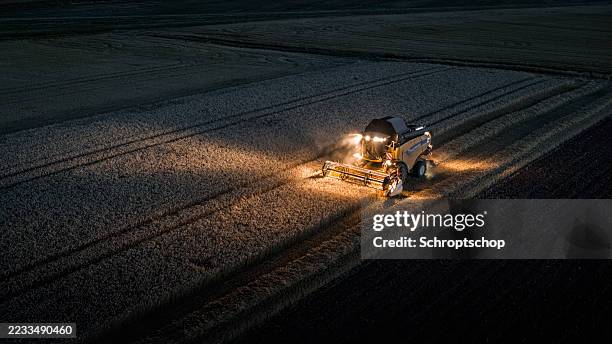 combine harvesting wheat at night, aerial view - agricultural equipment stock pictures, royalty-free photos & images
