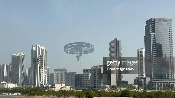 the large circular spaceship floats over a modern business district with high-rise towers. - space debris stock pictures, royalty-free photos & images