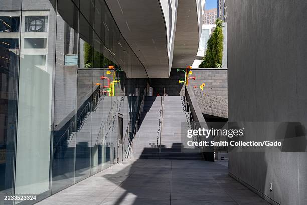 Modern outdoor stairway with glass facade, deep shadows, and colorful public art elements outside SFMOMA, San Francisco Museum of Modern Art, San...