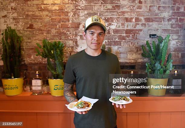 Owner Adrian Hurtado holds an al pastor and vegetarian taco during the grand opening of Tacos 203 at the South Norwalk station in Norwalk, Conn....
